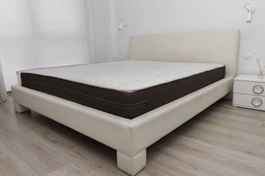 Sağlıklı uyku ve rahatlama için mükemmel bir yer. Temiz, minimalist yatak odasında rahat bir yatağı olan modern bir yatak. Görüntü konforu, rahatlığı ve modern iç tasarımı sembolize eder..