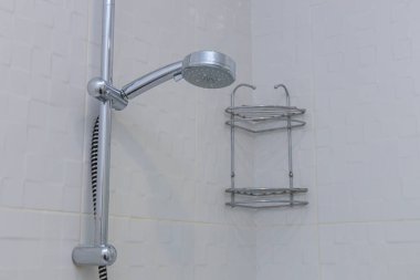 Modern bir iç mekanda temizlik ve işlevsellik. Bir duş başlığı ve raf görüntüsü, bir ev veya otel odasında hijyen, konfor ve tesisatın önemini vurgular..