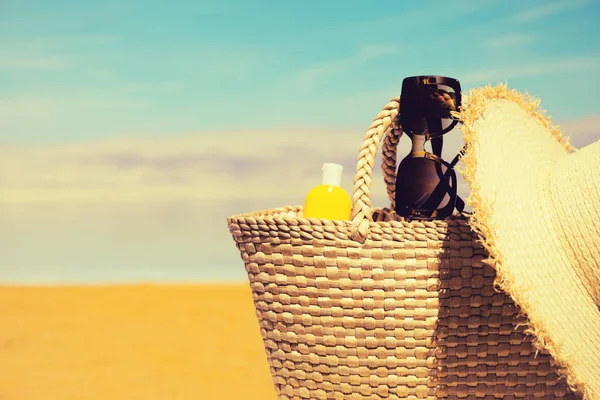 Saco de palha, óculos de sol, uma garrafa de protetor solar e um chapéu wi — Fotografia de Stock