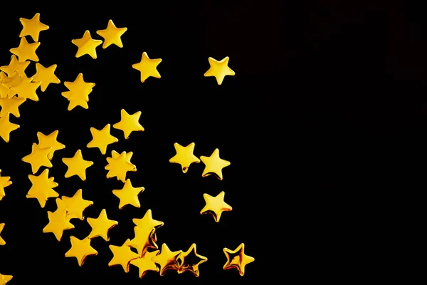 Estrelas decorativas douradas sobre fundo preto — Fotografia de Stock