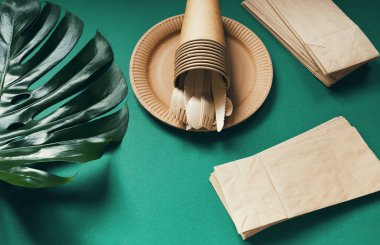 Çevre dostu kağıt sofra takımı yeşil arka planda canavar yapraklı. Geri dönüşüm konsepti. Üst Manzara. Uzayı kopyala Hiç atık teması.