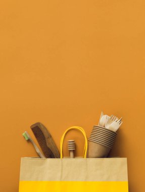 Çevre dostu kağıt bardaklar, tahta çatallar, kaşıklar, bıçaklar, bombu diş fırçası ve renkli arka planda tarak. Geri dönüşüm konsepti. Sıfır atık teması Doğal malzemeler. Üst Manzara. Düz yatıyordu