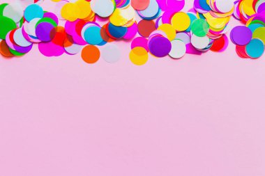 Renkli şenlik konfetileri, pembe arka planda mevsimlik davetiyeler ve web tasarımı için bir çerçeve olarak yalan söylüyorlar. Parti konsepti. Düz yatıyordu. Boşluğu kopyala