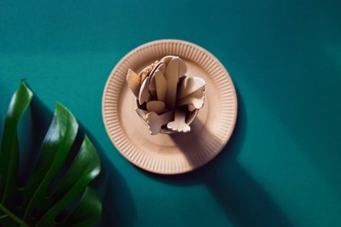 Çevre dostu kağıt sofra takımı yeşil arka planda canavar yapraklı. Geri dönüşüm konsepti. Üst Manzara. Uzayı kopyala Hiç atık teması.