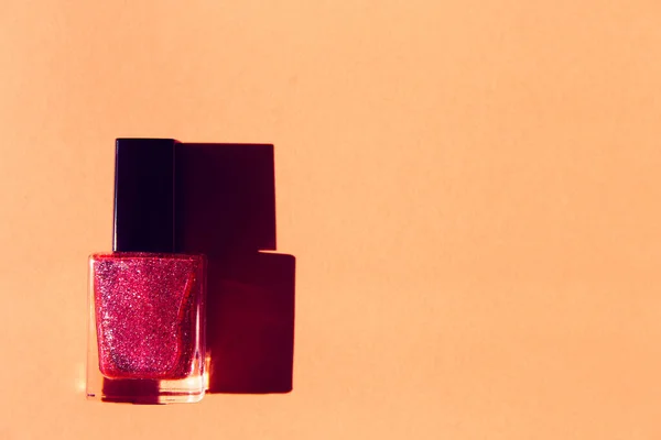 A bottle  of glittering nail polish with the shade on colorful  background . Top view. Flat lay. Creative layout. Minimal style composition