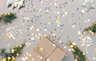 Pastel arka planda ardıç dalı, dekoratif köknar ağacı, toplar, gümüş kar taneleri, yıldızlar ve pullarla birlikte el sanatları hediye kutusu. Noel hediyesi. Kutlama ve parti konsepti. Düz yatıyordu. Üst görünüm