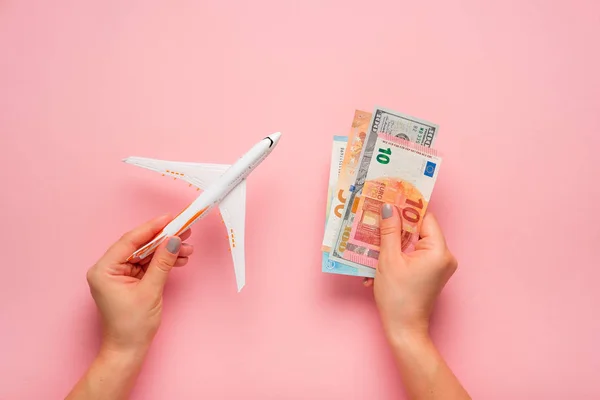 Самолет и деньги на розовом фоне. Концепция путешествия . — стоковое фото