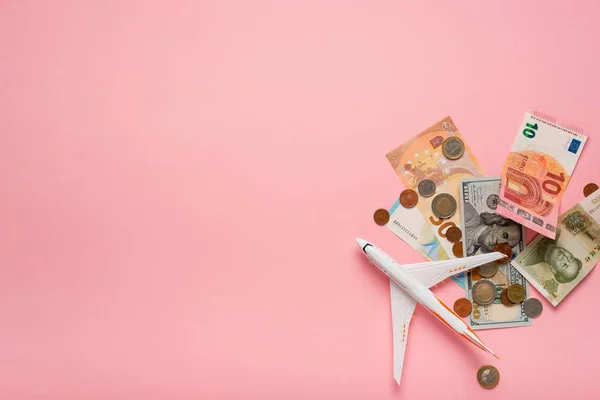 Avión y dinero sobre un fondo rosa. Concepto de viaje . —  Fotos de Stock