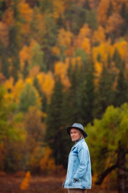 Sonbahar orman arka plan üzerinde şapkalı güzel ve genç birbayan. Sonbaharda manzara. 