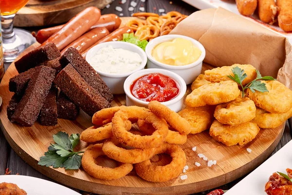 Bira aperatifler kapatın. Izgara sosis, soğan halkaları ve soslar ile nuggets