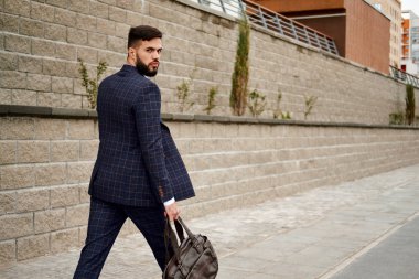 Çekici işadamı seyahat çantası elinde sokakta yürürken