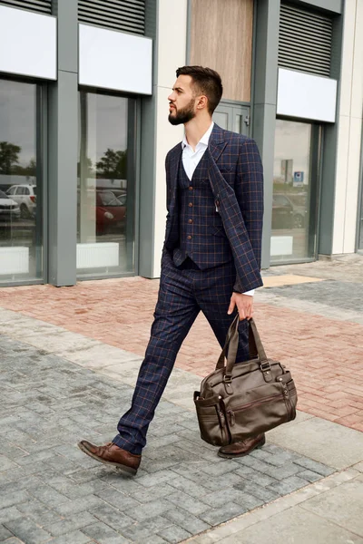 Attractive businessman walking down the street holding travel bag — Stock Photo, Image