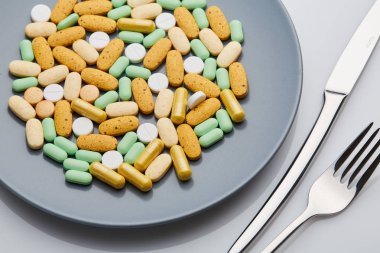 Tabak çatal ve bıçak beyaz arka plan üzerinde renkli hap