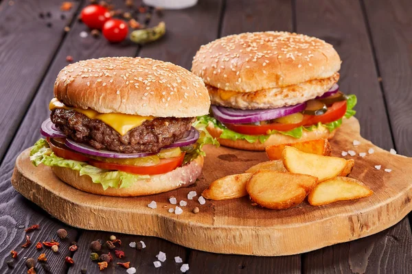 Lekker vers vlees hamburgers met salade en kaas geserveerd op houten plank. — Stockfoto