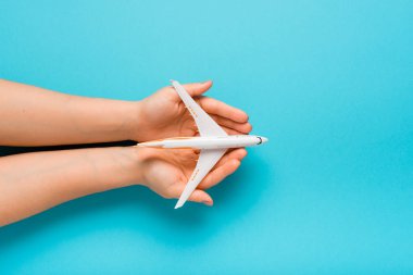 Dikkatle maket uçak tutan el. Mavi renk arka plan uçakta. Güvenlik kavramı.