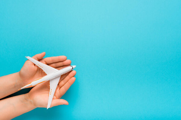 Hand carefully holding model plane. Airplane on blue color background. Security concept.