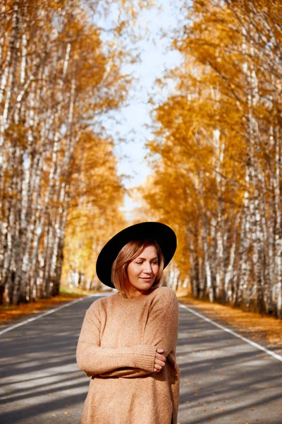Portrait of an autumn woman over golden leaves. Woman walking in park at autumn season