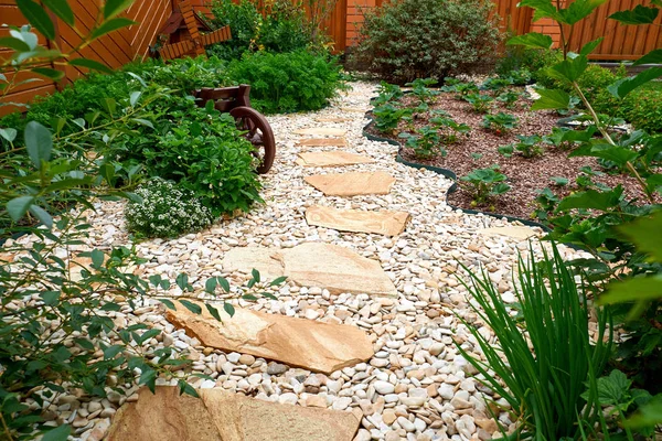 Garden Design. Pathway in garden, Flowers with bricks pathways. The care of garden plants