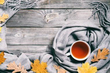 Sonbahar kompozisyon, sonbahar yaprakları, dumanı tüten fincan çay ve sıcak bir eşarp ahşap masa arka plan üzerinde sıcak. Retro tonlama