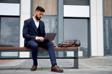 Dizüstü bilgisayar üzerinde çalışan iş adam. İş takım elbiseli adam açık havada üzerinde