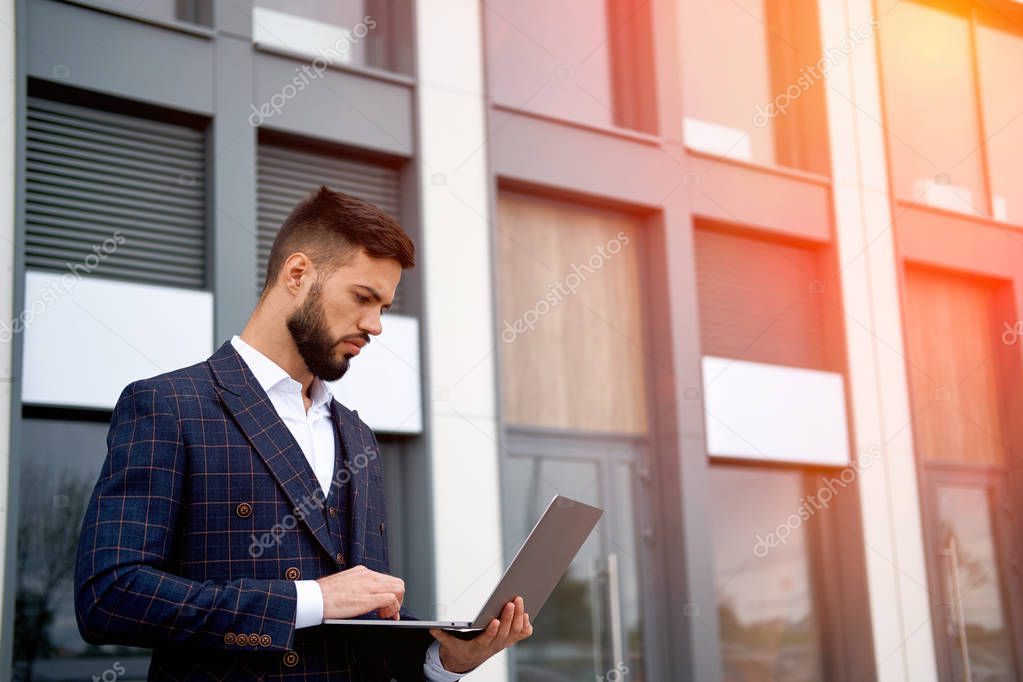 Business Man Working on Laptop Computer. Man in Business Suit on outdoors. Sun Glare