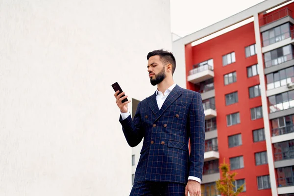 Businessman urban professional business man using mobile phone at office building in city. Professional wearing suit jacket.