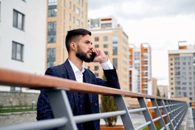 Sakallı işadamı telefon ve güler tarafından konuşuyor. Akıllı telefon kullanan genç çekici iş adam. Müşteriler ile cep telefonuyla konuşan işadamı