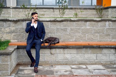 Sakallı işadamı telefon ve güler tarafından konuşuyor. Akıllı telefon kullanan genç çekici iş adam. Müşteriler ile cep telefonuyla konuşan işadamı