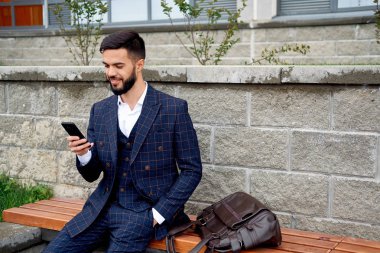 Sakallı işadamı telefon ve güler tarafından konuşuyor. Akıllı telefon kullanan genç çekici iş adam. Müşteriler ile cep telefonuyla konuşan işadamı