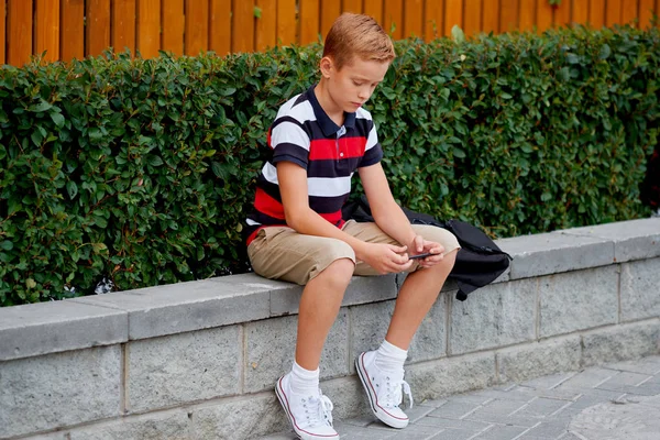 Dış okul oturma ve cep telefonundan oyun çocuk — Stok fotoğraf
