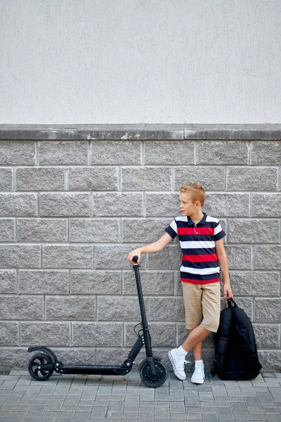 学校男孩在站立与他的电动滑板车在城市与背包 — 图库照片