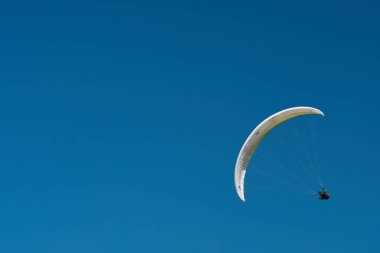 Yamaçparaşütü mavi gökyüzünde uçuyor. Güneşli bir havada yamaç paraşütü.