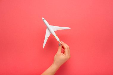Dikkatle maket uçak tutan el. Pembe renkli arka plan üzerinde uçak. Güvenlik kavramı.