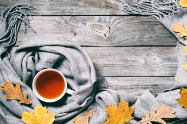 Sonbahar kompozisyon, sonbahar yaprakları, dumanı tüten fincan çay ve sıcak bir eşarp ahşap masa arka plan üzerinde sıcak. Retro tonlama