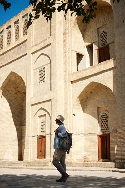 Jonge vrouwelijke reiziger met rugzak en hoed op de straat. Travel concept. Buchara, Oezbekistan — Stockfoto