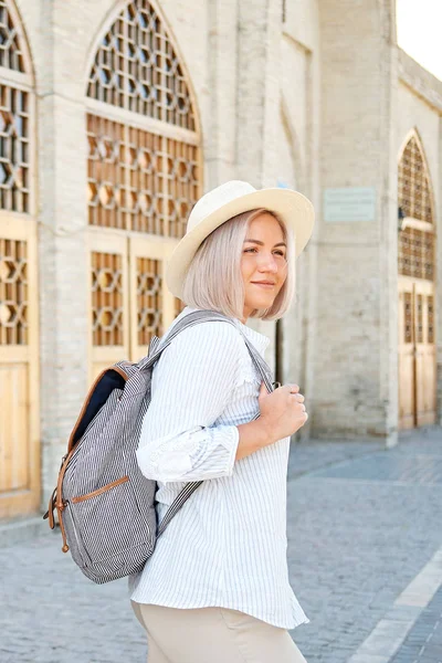 Mladé samice cestovatel s batohem a s kloboukem na ulici. Cestovní koncept. Uzbekistán, buchary — Stock fotografie