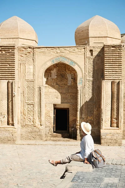 Achteraanzicht van mooie vrouw permanent en kijken naar bezienswaardigheden, een populaire bestemming in Oezbekistan, Buchara — Stockfoto