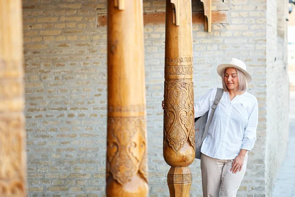 Jonge vrouwelijke reiziger met rugzak en hoed op de straat. Travel concept. Buchara, Oezbekistan — Stockfoto