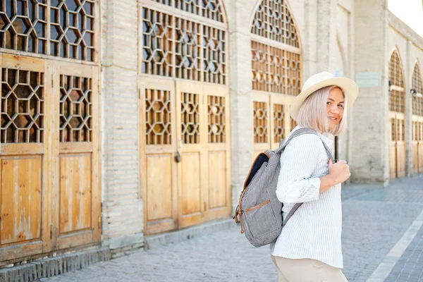 Young female traveler with backpack and with hat on the street. Travel concept. Uzbekistan, Bukhara — Stock Photo, Image