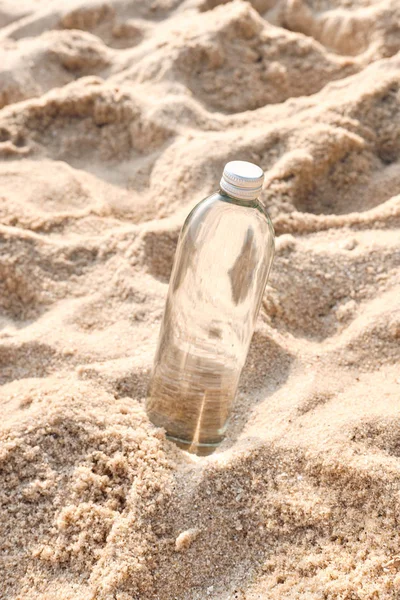 Bottiglia riutilizzabile in vetro trasparente sulla sabbia della spiaggia — Foto Stock
