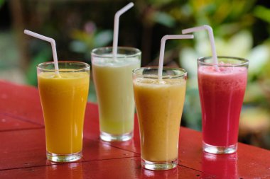 Sağlıklı Taze Farklı Meyve Smoothie Kokteyl İçeceği. Kahvaltı için Yeşil ve Turuncu Karışık Karışık Karışık Diyet İçeceği. Kırmızı Kırsal Arkaplanda Organik Yaz Tatlı Meyve Suyu Harmanı