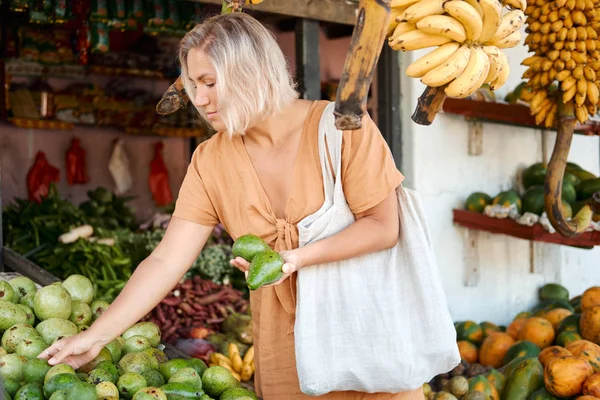 Kobieta kupuje organiczne awokado na tropikalnym rynku wiejskim. Sklep spożywczy — Zdjęcie stockowe