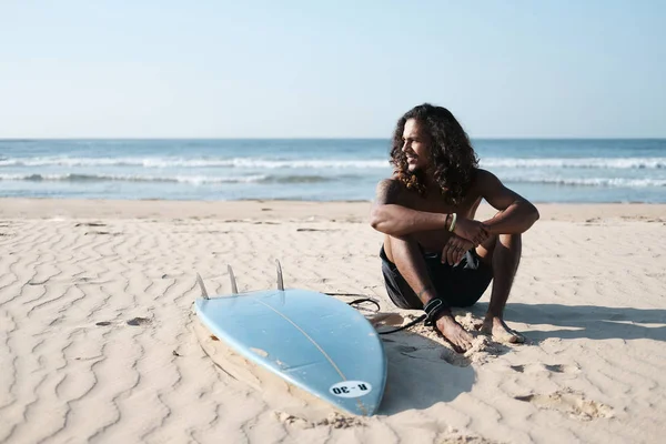 Surfista con tavola da surf sulla spiaggia. Razza mista pelle nera e barba. Attività sportive estive — Foto Stock