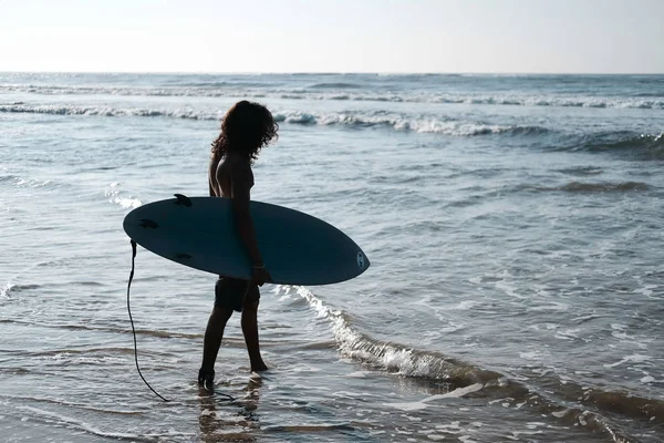 Surfista con tavola da surf sulla spiaggia. Razza mista pelle nera e barba. Attività sportive estive — Foto Stock