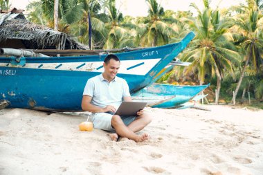 Adam Freelancer iş dizüstü bilgisayar tarafından oturmak okyanus plaj