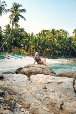Mutlu kadın Rock tarafından tropikal plaj palmiye ağacı üzerinde
