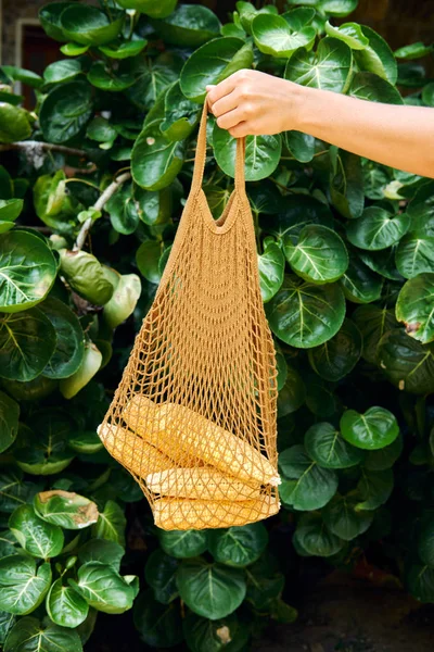 在生态网袋中手持新鲜甜玉米 — 图库照片