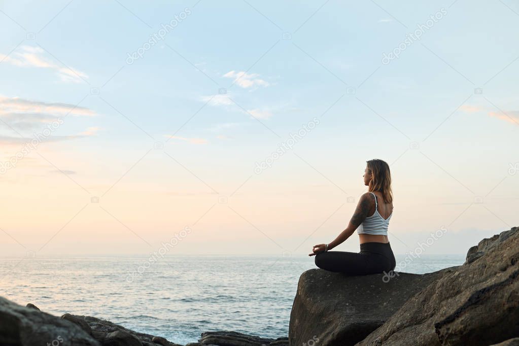 Woman Practicing Yoga in the Nature. Meditating Outdoors. Landscape background