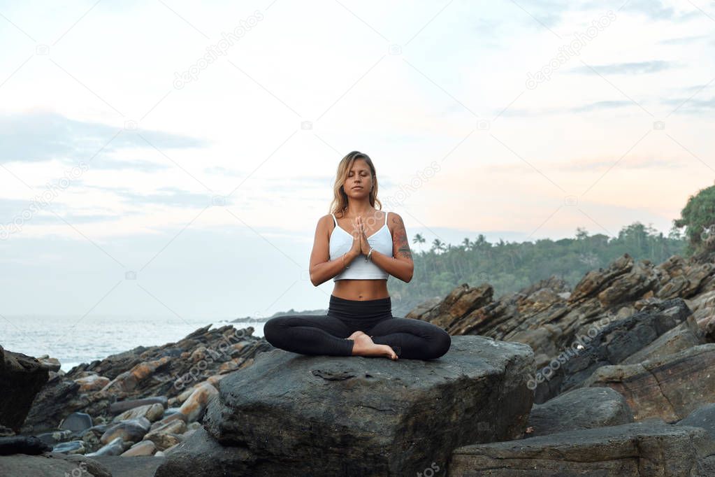 Woman Practicing Yoga in the Nature. Meditating Outdoors. Landscape background