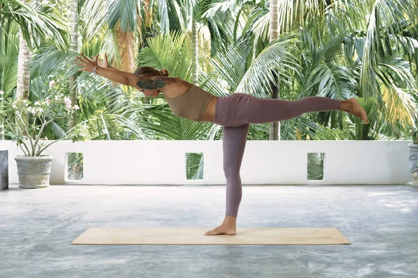 Kobieta ćwiczy zaawansowaną jogę na macie organicznej. Seria pozów jogi. Kontekst tropikalny — Zdjęcie stockowe